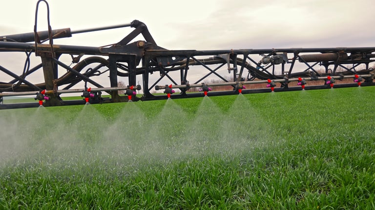 Agricultural sprayer applying liquid fertilizer on green crop field