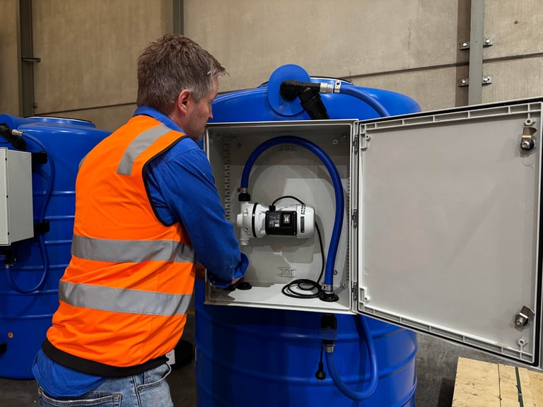 Worker in orange safety vest opening a door on a blue industrial tank or equipment